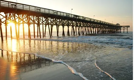 A pier with the sun setting over the ocean.