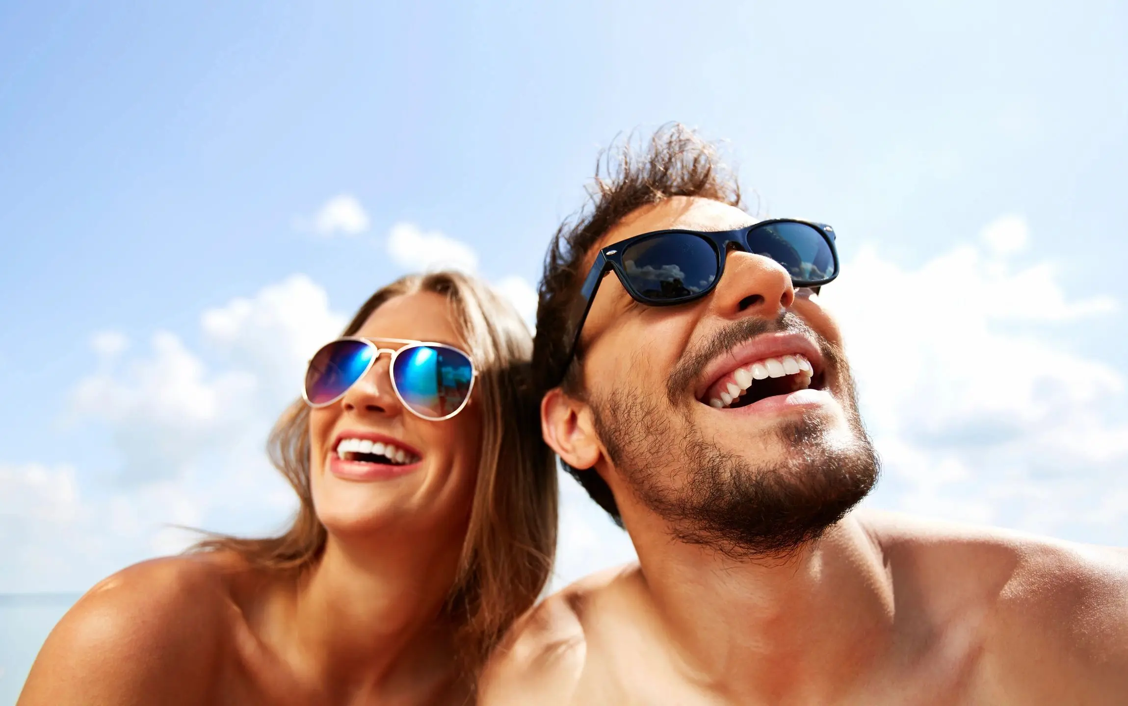 A man and woman wearing sunglasses smiling for the camera.