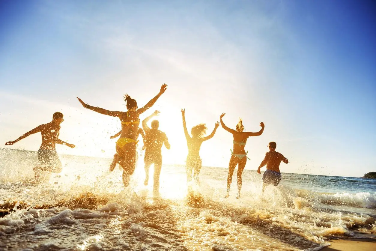 A group of people jumping in the air on top of a beach.