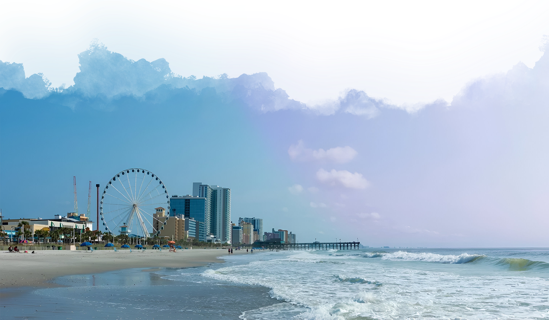 A beach with waves and buildings in the background.