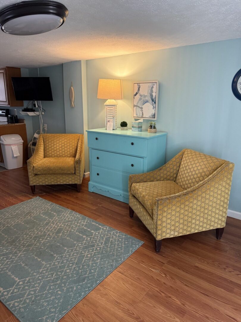 Yellow armchairs beside turquoise dresser and lamp