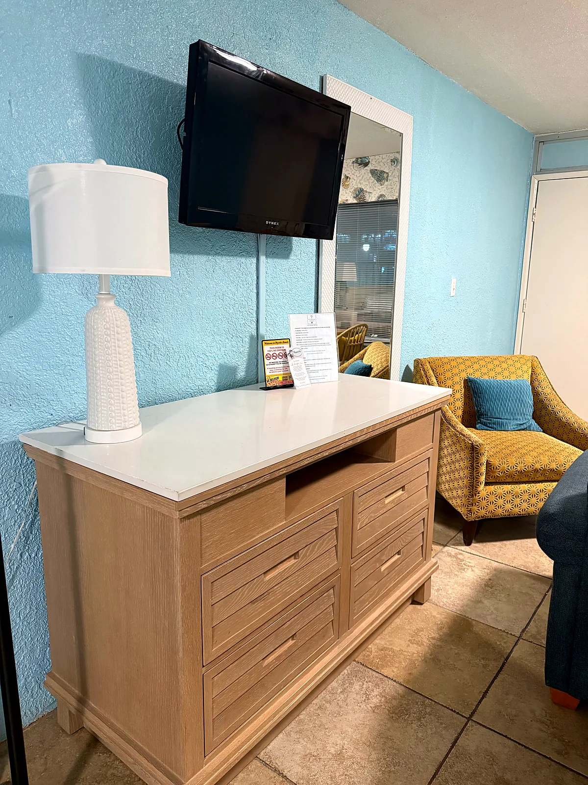 Dresser with TV and accent chair in king room