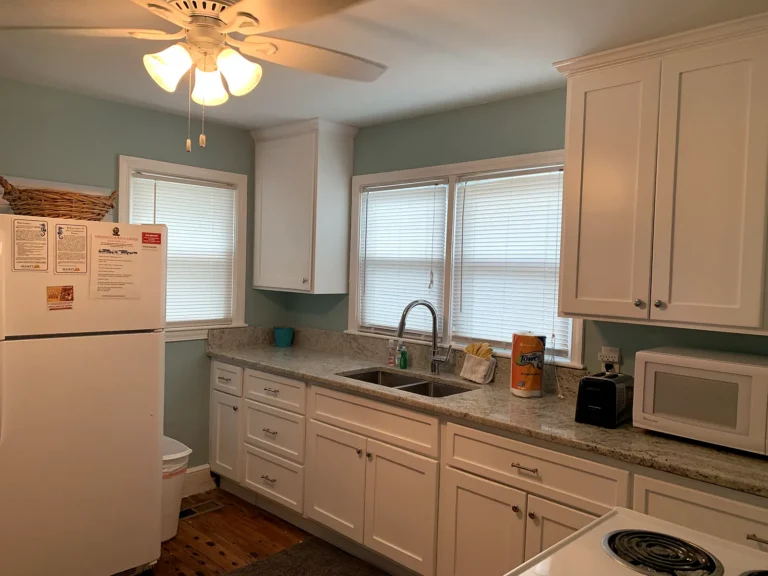 A Beach Cottage renovated kitchen with white cabinets and granite counters
