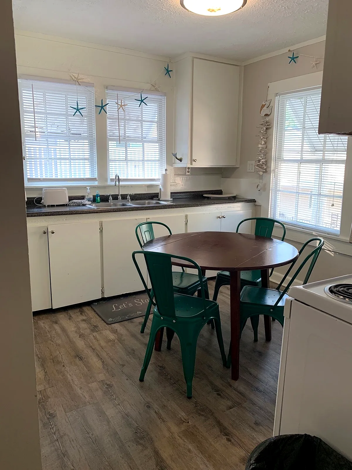 Palmetto Cottage kitchen with white cabinets and green chairs