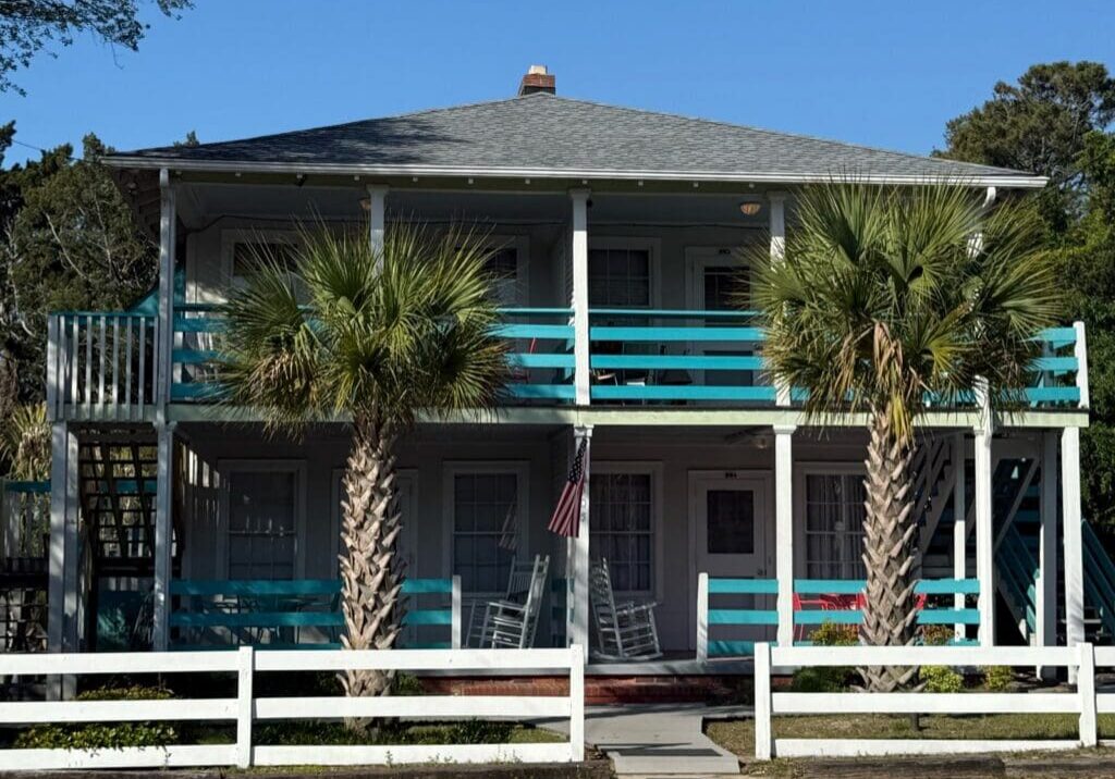 Boardwalk Cottage at the Darlington Inn & Cottages, a two-story cottage with teal porch railings and palm trees